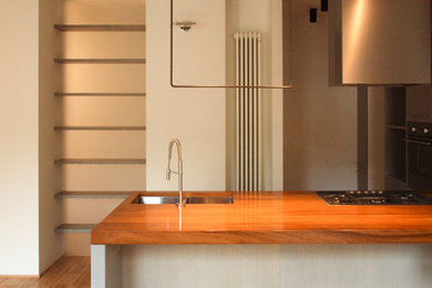 Ispirazione per una cucina design di medie dimensioni con ante lisce, ante grigie, penisola, lavello sottopiano, top in legno, elettrodomestici da incasso e pavimento in legno massello medio