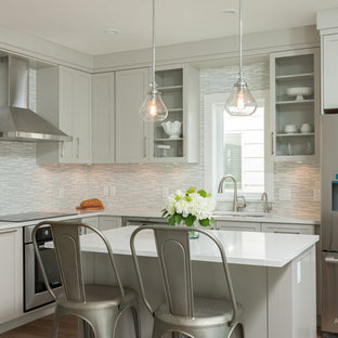 Mid-sized craftsman kitchen pantry remodeling - Inspiration for a mid-sized craftsman l-shaped medium tone wood floor kitchen pantry remodel in Vancouver with an undermount sink, shaker cabinets, white cabinets, gray backsplash, ceramic backsplash, stainless steel appliances and an island