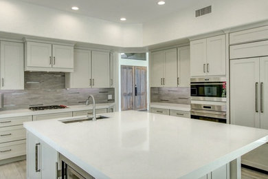 Photo of a mid-sized modern kitchen in Phoenix with an undermount sink, shaker cabinets, white cabinets, quartz benchtops, grey splashback, mosaic tile splashback, stainless steel appliances, porcelain floors, with island, beige floor and white benchtop.