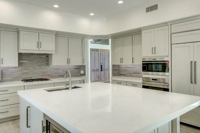 Inspiration for a mid-sized modern porcelain tile and beige floor kitchen remodel in Phoenix with an undermount sink, shaker cabinets, white cabinets, quartz countertops, gray backsplash, mosaic tile backsplash, stainless steel appliances, an island and white countertops