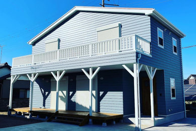 Modelo de fachada de casa azul costera de tamaño medio de dos plantas con revestimientos combinados