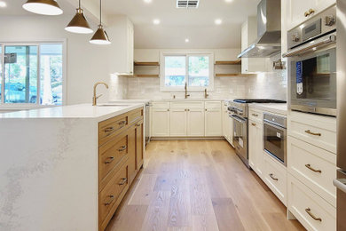 Mid-sized country u-shaped light wood floor kitchen photo in Los Angeles with a single-bowl sink, shaker cabinets, white cabinets, quartz countertops, white backsplash, subway tile backsplash, stainless steel appliances, an island and white countertops