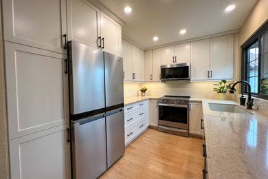Mid-sized elegant u-shaped laminate floor and brown floor enclosed kitchen photo in San Diego with an undermount sink, shaker cabinets, white cabinets, quartz countertops, beige backsplash, ceramic backsplash, stainless steel appliances, no island and beige countertops