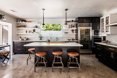 Eat-in kitchen - mid-sized contemporary l-shaped concrete floor and gray floor eat-in kitchen idea in Los Angeles with a single-bowl sink, shaker cabinets, black cabinets, quartzite countertops, white backsplash, stone slab backsplash, stainless steel appliances, an island and white countertops