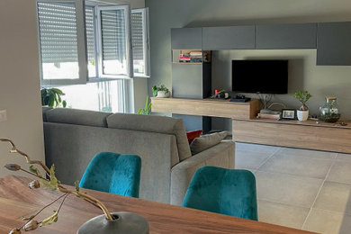 Imagen de salón abierto contemporáneo de tamaño medio con paredes grises, suelo de baldosas de porcelana, televisor colgado en la pared y suelo gris
