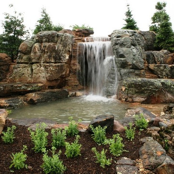 Waterfall flowing over 10 foot tall Grotto Cave at Worlds most extreme pond in S