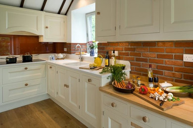 This is an example of a mid-sized traditional l-shaped eat-in kitchen in Other with an undermount sink, beaded inset cabinets, quartz benchtops, orange splashback, light hardwood floors and no island.