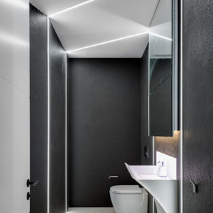 Aménagement d'une petite salle de bain contemporaine avec un placard avec porte à panneau encastré, des portes de placard noires, un carrelage noir, carrelage en mosaïque, un plan de toilette en surface solide et un plan de toilette blanc.