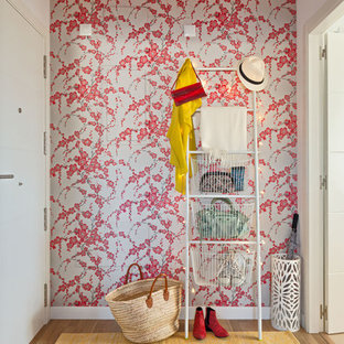 Réalisation d'une petite porte d'entrée bohème avec un sol en bois brun, un mur rose, une porte simple et une porte blanche.