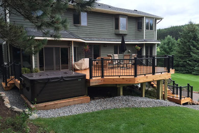 Example of a large classic backyard deck design in Minneapolis with a pergola