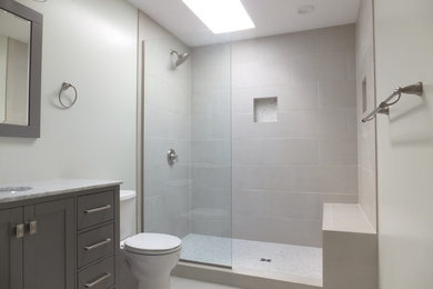 Photo of a mid-sized transitional 3/4 bathroom in Orange County with shaker cabinets, grey cabinets, an open shower, a two-piece toilet, grey walls, slate floors, an undermount sink, marble benchtops, beige tile, ceramic tile, grey floor and an open shower.