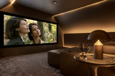 Modelo de cine en casa cerrado contemporáneo de tamaño medio con paredes grises, moqueta, pantalla de proyección y suelo gris