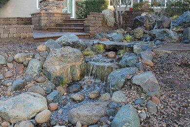 This is an example of a backyard garden in Sacramento with a water feature and natural stone pavers.