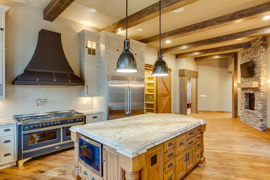 Huge mountain style u-shaped medium tone wood floor eat-in kitchen photo in Other with a farmhouse sink, beaded inset cabinets, beige cabinets, granite countertops, beige backsplash, mosaic tile backsplash, stainless steel appliances and an island