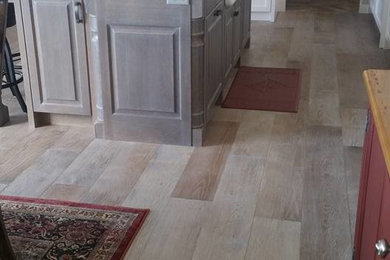 Example of a mid-sized classic single-wall light wood floor eat-in kitchen design in Houston with an island