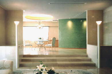 Offenes Modernes Wohnzimmer mit beiger Wandfarbe, Marmorboden, beigem Boden, Kamin und Kaminumrandung aus Stein
