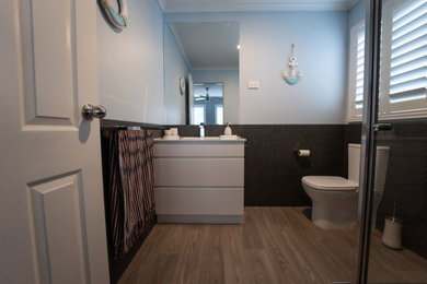 Photo of a small modern bathroom in Other with white cabinets, gray tile, porcelain tile, blue walls, vinyl floors, solid surface benchtops, brown floor, white benchtops, a niche, a single vanity and a freestanding vanity.