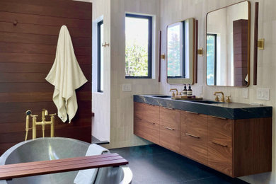 Bathroom - large contemporary beige tile and ceramic tile porcelain tile, black floor, double-sink, vaulted ceiling and wood wall bathroom idea in New York with flat-panel cabinets, brown cabinets, a bidet, white walls, an undermount sink, soapstone countertops, black countertops and a floating vanity