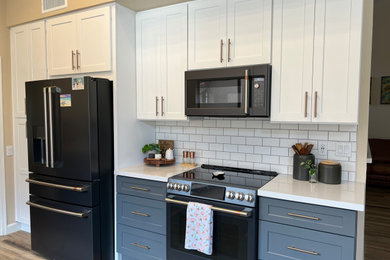 Photo of a large country galley open plan kitchen in Phoenix with a farmhouse sink, shaker cabinets, grey cabinets, quartz benchtops, white splashback, subway tile splashback, black appliances, a peninsula, white benchtop and vaulted.