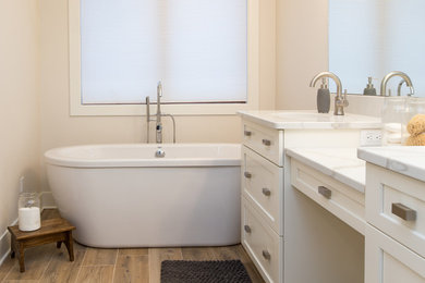 Inspiration for a mid-sized country master beige tile and porcelain tile porcelain tile and brown floor bathroom remodel in Other with shaker cabinets, white cabinets, a two-piece toilet, beige walls, an undermount sink and quartz countertops