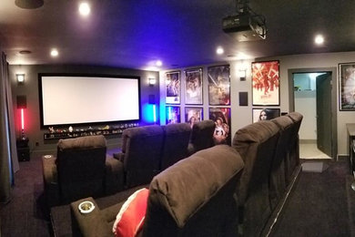 Imagen de cine en casa cerrado minimalista de tamaño medio con paredes grises, moqueta, pantalla de proyección y suelo negro