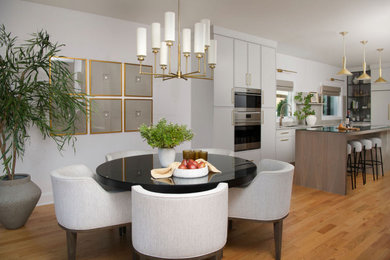 Example of a mid-sized minimalist l-shaped medium tone wood floor eat-in kitchen design in Charlotte with a drop-in sink, gray cabinets, quartzite countertops, beige backsplash, stone slab backsplash, stainless steel appliances, an island and beige countertops