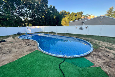 Pool landscaping - large contemporary backyard concrete paver and custom-shaped natural pool landscaping idea in New York