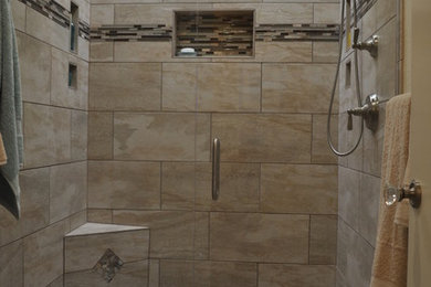 Inspiration for a mid-sized contemporary master bathroom in Sacramento with an alcove shower, beige tile, black tile, brown tile, gray tile, multi-coloured tile, pebble tile, a one-piece toilet, beige walls, ceramic floors and a hinged shower door.