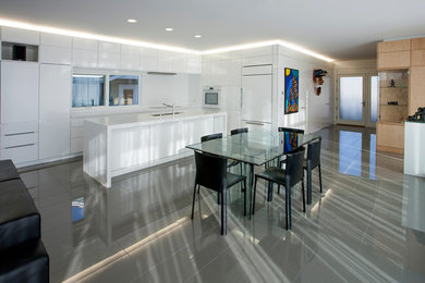Inspiration for a mid-sized modern l-shaped porcelain tile eat-in kitchen remodel in Calgary with an undermount sink, flat-panel cabinets, white cabinets, solid surface countertops, white backsplash, glass sheet backsplash, white appliances and an island