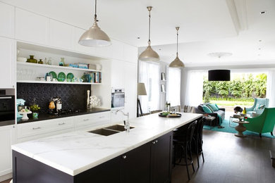 Mid-sized single-wall open plan kitchen in Sydney with a double-bowl sink, beaded inset cabinets, white cabinets, marble benchtops, black splashback, metal splashback, stainless steel appliances, dark hardwood floors and with island.