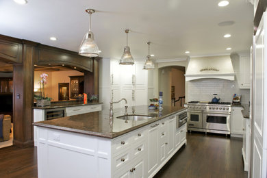 Large elegant l-shaped dark wood floor kitchen photo in San Francisco with an undermount sink, raised-panel cabinets, white cabinets, granite countertops, white backsplash, subway tile backsplash, paneled appliances and an island