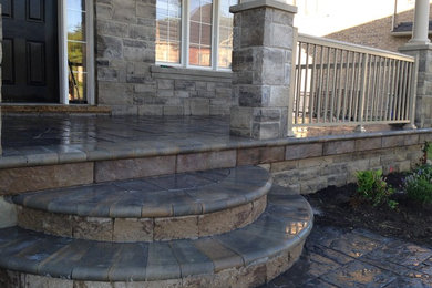 This is an example of a mid-sized front yard verandah in Toronto with concrete pavers and a roof extension.