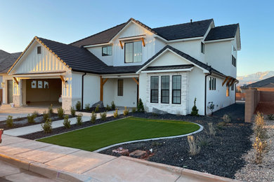 Cottage white two-story stucco and board and batten exterior home photo in Salt Lake City with a tile roof and a black roof