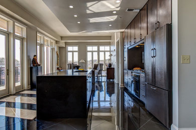 Inspiration for a small modern galley porcelain tile open concept kitchen remodel in Birmingham with a single-bowl sink, flat-panel cabinets, gray cabinets, granite countertops, black backsplash, stone slab backsplash, paneled appliances and an island