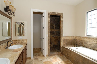 Inspiration for a large timeless master beige tile and travertine tile travertine floor and beige floor bathroom remodel in Phoenix with raised-panel cabinets, dark wood cabinets, beige walls, a drop-in sink, tile countertops, a hinged shower door and beige countertops