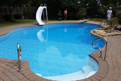 Example of a large classic backyard brick and custom-shaped pool design in Wilmington