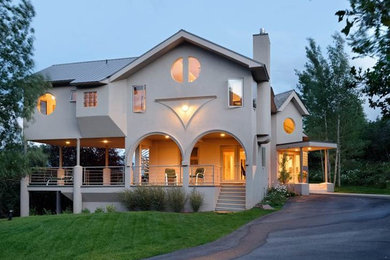 Large modern beige two-story stucco gable roof idea in Denver