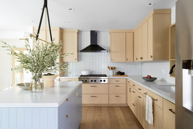 Example of a large trendy l-shaped medium tone wood floor eat-in kitchen design in San Francisco with an undermount sink, recessed-panel cabinets, light wood cabinets, quartz countertops, white backsplash, ceramic backsplash, stainless steel appliances, an island and gray countertops