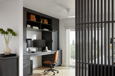 Example of a trendy built-in desk light wood floor home office design in San Francisco with white walls