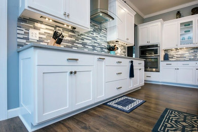 Inspiration for a mid-sized transitional single-wall dark wood floor and brown floor enclosed kitchen remodel in Columbus with a farmhouse sink, shaker cabinets, white cabinets, granite countertops, multicolored backsplash, matchstick tile backsplash, stainless steel appliances, an island and gray countertops