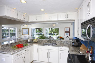 Photo of a mid-sized traditional l-shaped eat-in kitchen in Tampa with a single-bowl sink, recessed-panel cabinets, light wood cabinets, granite benchtops, blue splashback, stainless steel appliances, limestone floors, ceramic splashback and beige floor.