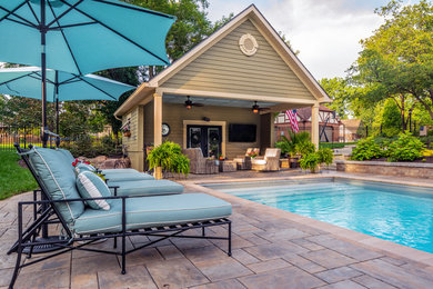 Photo of a large traditional backyard rectangular pool in Cincinnati with a pool house and brick pavers.