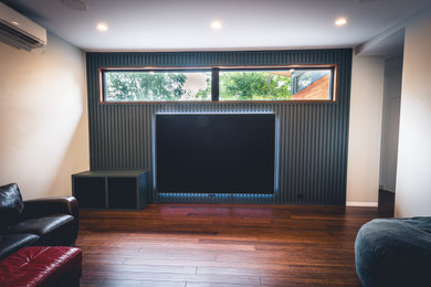 Diseño de cine en casa minimalista de tamaño medio con suelo de madera oscura y pared multimedia