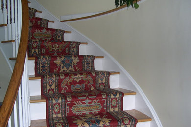 Mid-sized traditional carpeted curved staircase in New York with carpet risers and wood railing.