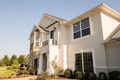 Example of a large transitional beige two-story stucco exterior home design in Other with a shingle roof