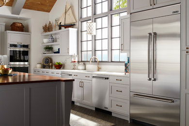 Inspiration for a transitional l-shaped dark wood floor and brown floor kitchen remodel in Portland with an undermount sink, recessed-panel cabinets, white cabinets, white backsplash, marble backsplash, stainless steel appliances and an island