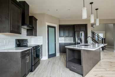 Mid-sized elegant single-wall light wood floor and beige floor eat-in kitchen photo in Calgary with an undermount sink, raised-panel cabinets, dark wood cabinets, marble countertops, white backsplash, subway tile backsplash, stainless steel appliances, an island and white countertops