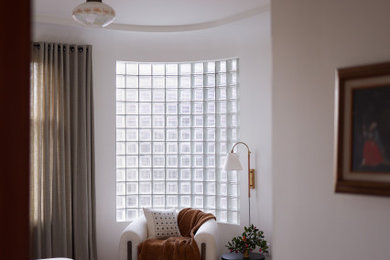 Cette photo montre une chambre parentale éclectique avec un mur blanc et un sol en bois brun.