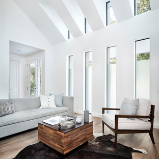 Inredning av ett modernt stort separat vardagsrum, med vita väggar, ett finrum, mörkt trägolv, en väggmonterad TV och brunt golv