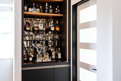 Inspiration for a small modern single-wall dry bar remodel in Seattle with flat-panel cabinets, mirror backsplash and black cabinets
